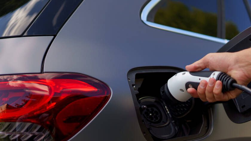 Man holding power supply cable at electric vehicle charging station, closeup