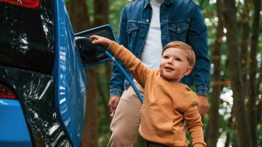 Father with his little son are waiting for electric car to charge