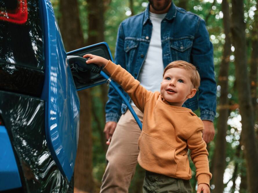 Father with his little son are waiting for electric car to charge